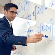 Feizi writing equations on white board.